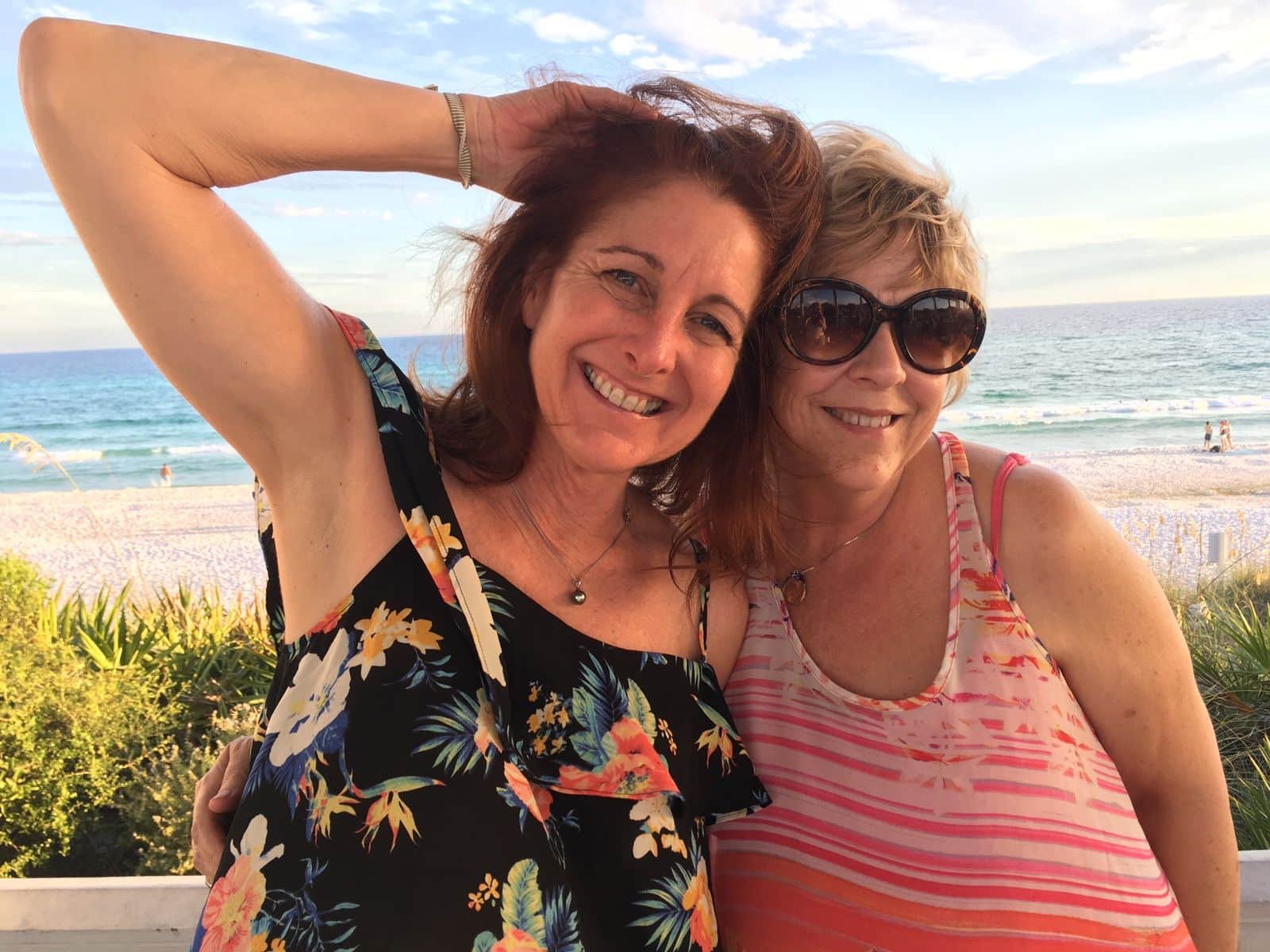 Alicia and a friend smiling together on a white-sand beach