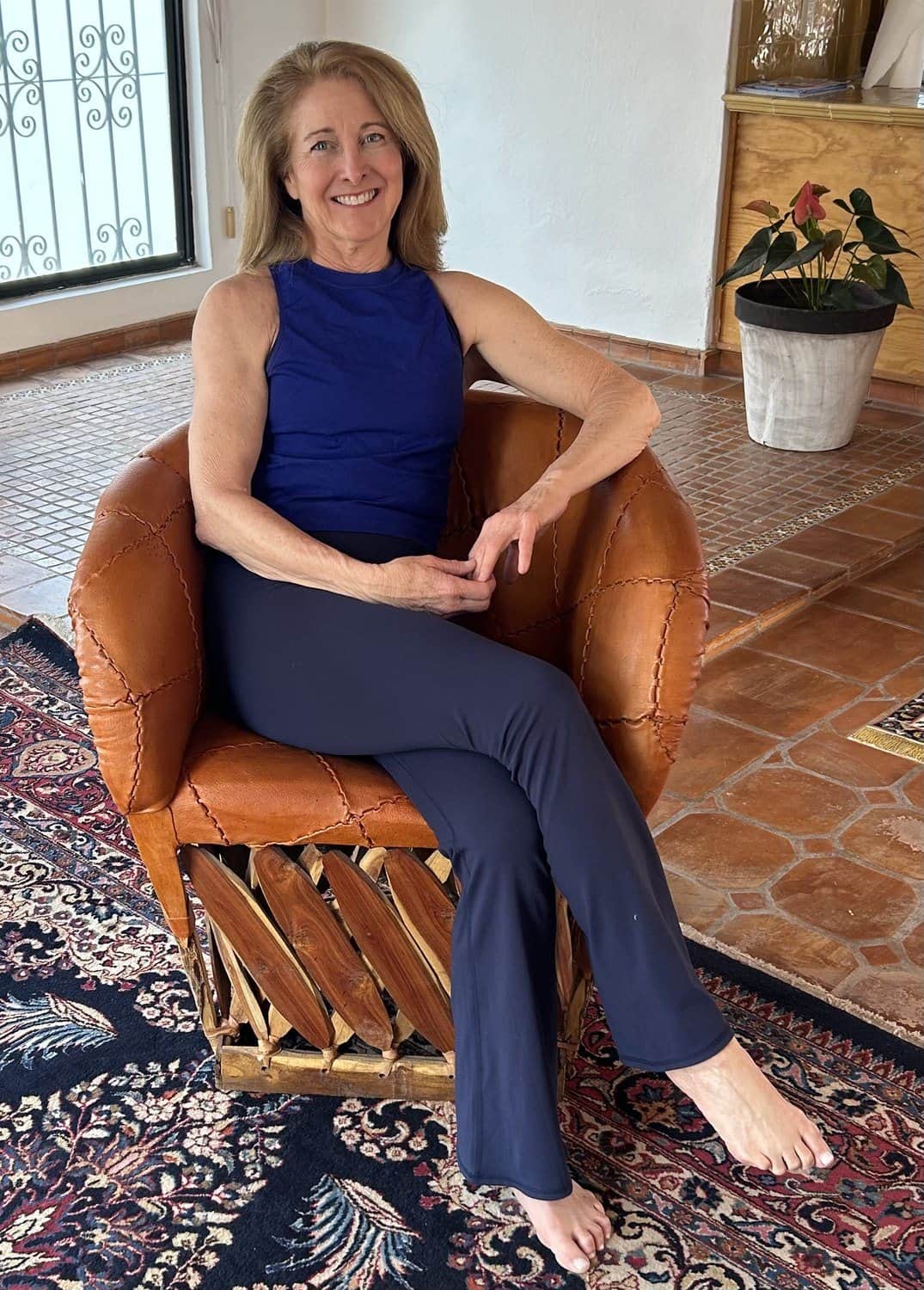 Alicia seated in a leather chair in a sunlit room