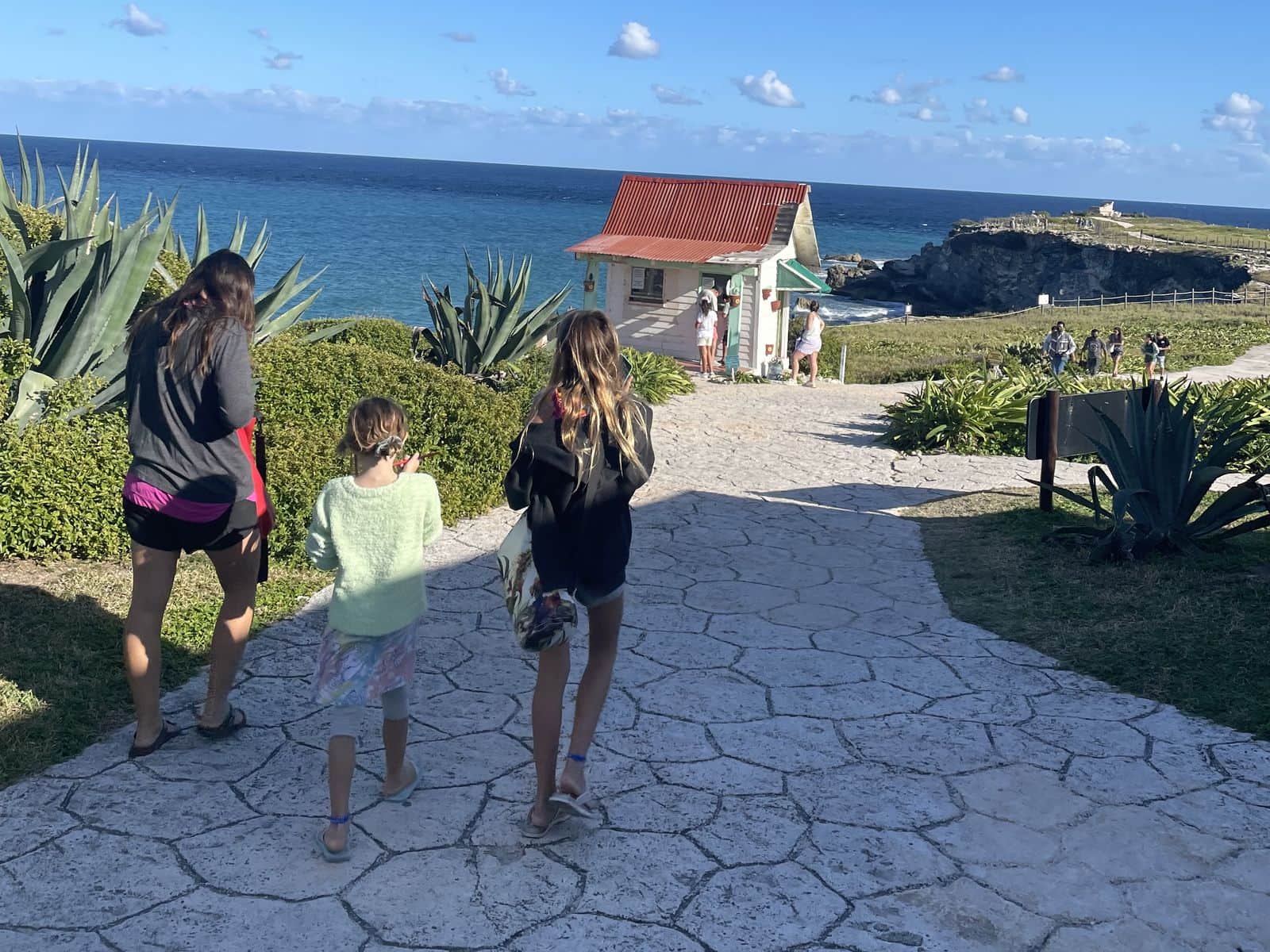A family walking down a stone path toward the sea