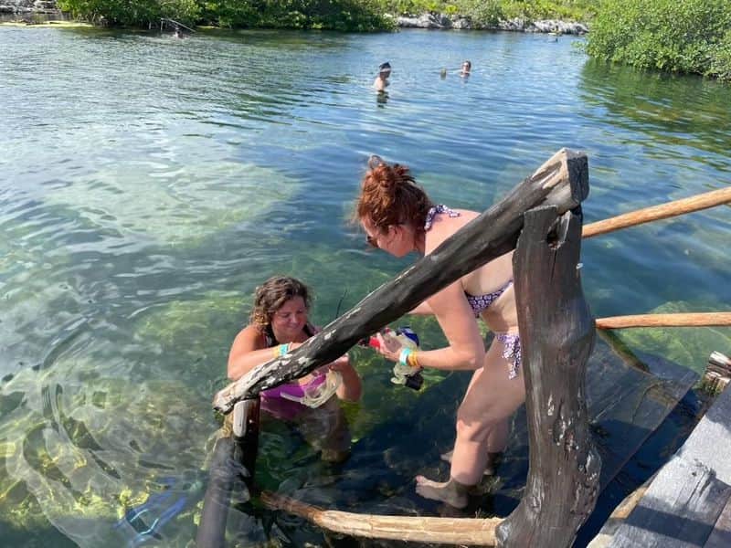 Alicia helping a retreat guest into the clear water of a cenote
