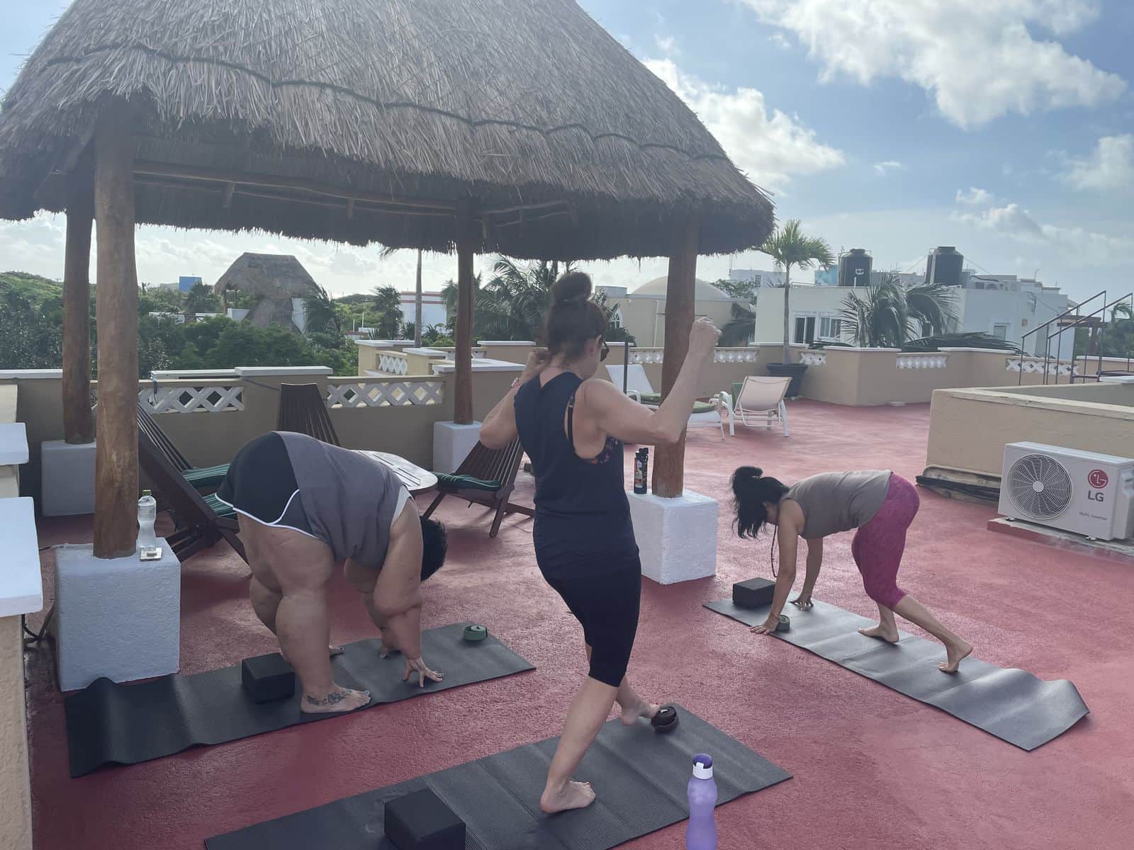 Retreat guests practicing on a rooftop beside a palapa