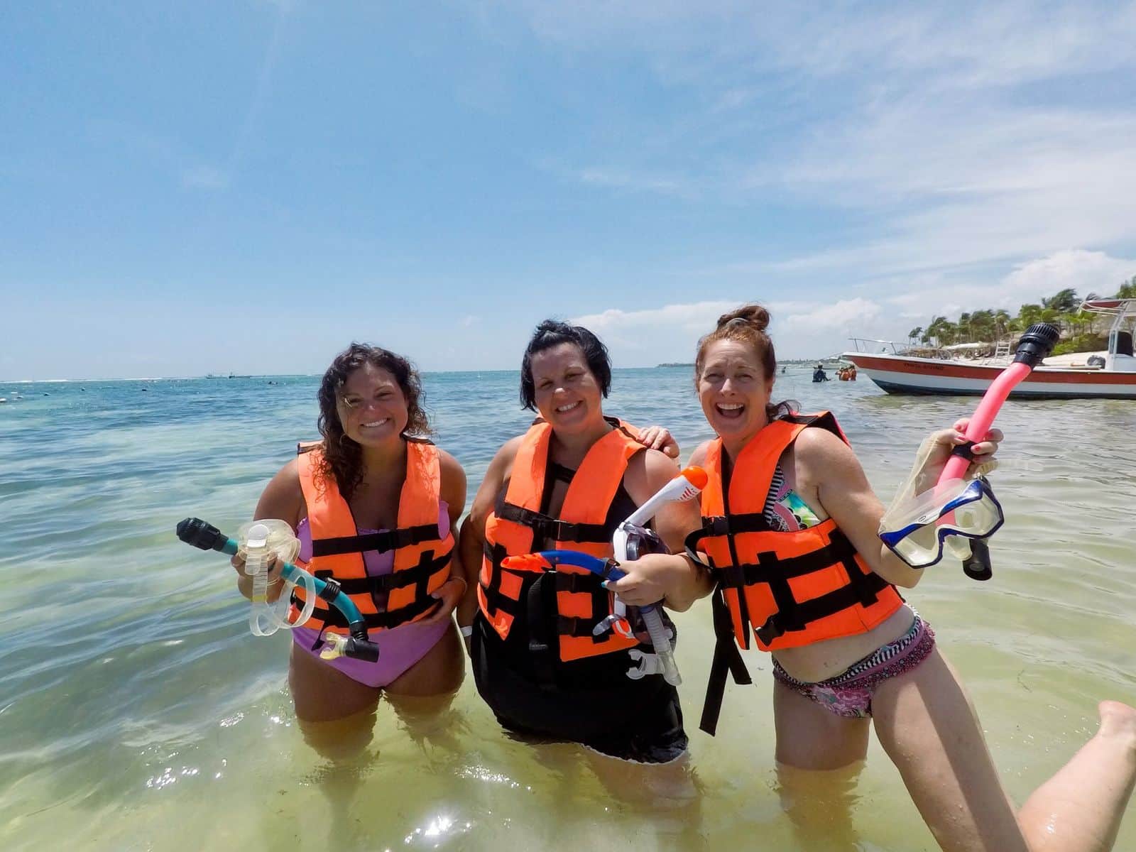 Alicia and two retreat guests in life jackets laughing in the sea before snorkeling