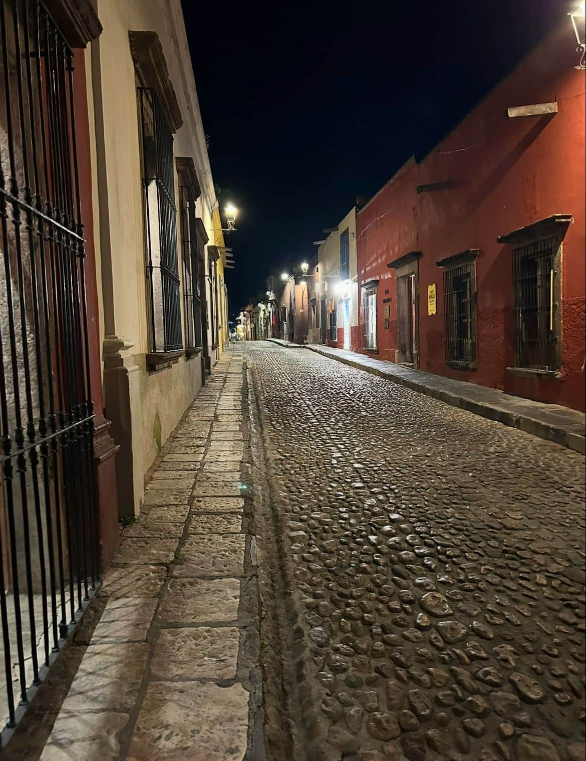A quiet cobblestone street in San Miguel de Allende at night