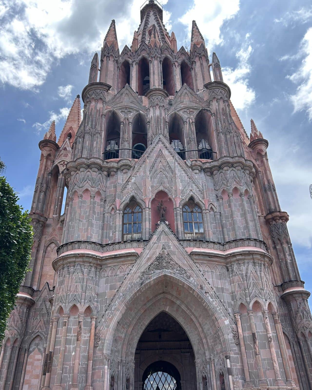 The pink stone spires of the Parroquia de San Miguel Arcángel against a blue sky